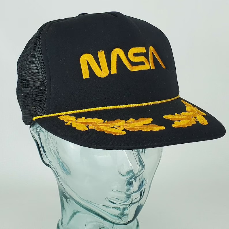 https://www.oldest.org/wp-content/uploads/2021/11/Vintage-80s-NASA-Embroidered-Gold-Logo-Black-Snapback-Trucker-Mesh-Hat-Cap.jpg